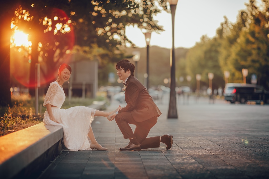 東京駅の一角で新婦に靴を履かせている茶色のタキシードを着た新郎
