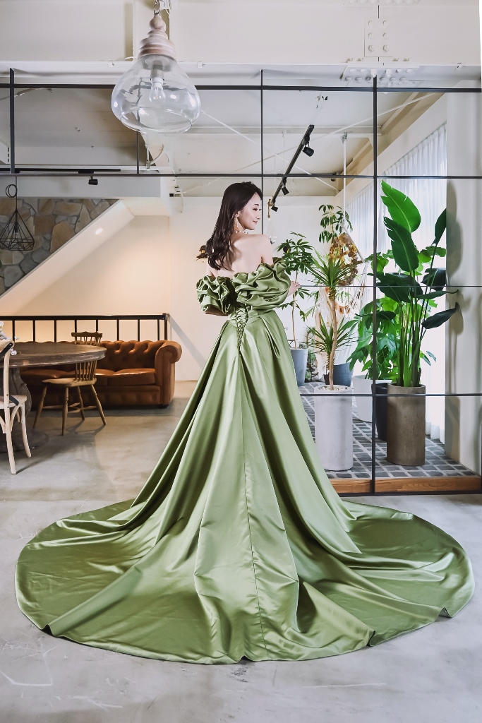 観葉植物のスタジオで振り返る、オリーブグリーンのサテンのカラードレスのロングトレーンの前撮りの衣装写真