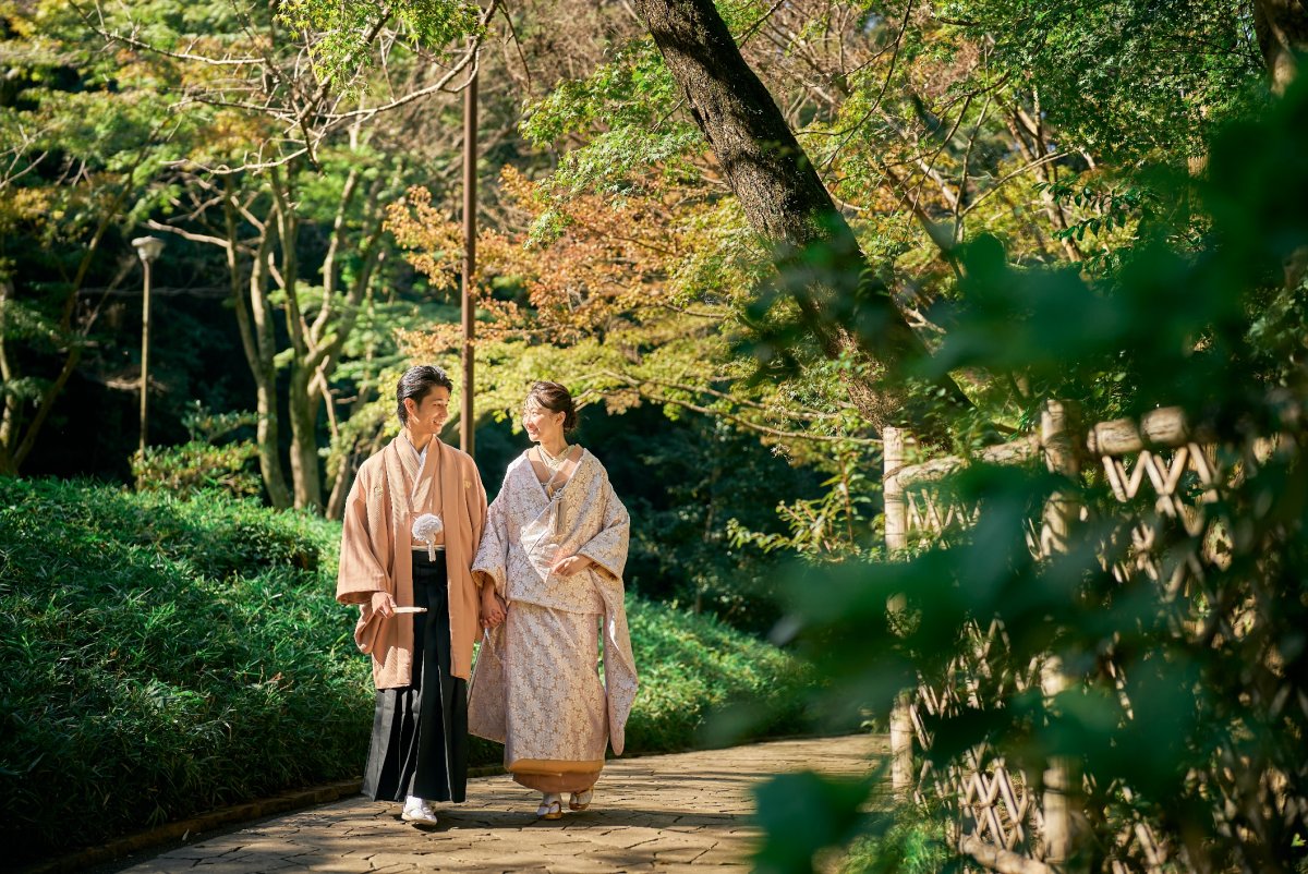 色づいた木々の小道を並んで歩く羽織袴の新郎と色打掛の花嫁。久良岐公園の秋の和装前撮り