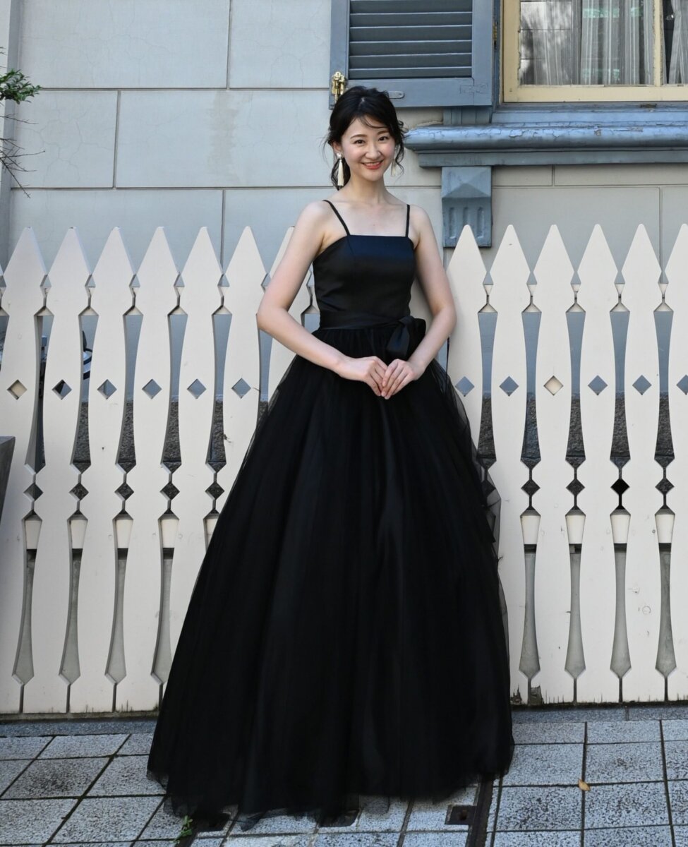 白い木の柵の前に立つ、ブラックのキャミソールのカラードレスの花嫁。街で撮る前撮りの衣装写真