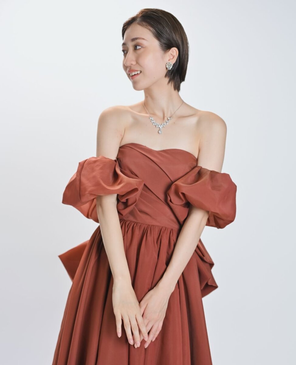 パフスリーブのテラコッタのカラードレスで手を重ねる、ショートヘアの花嫁のアップ。前撮りの衣装写真