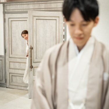 扉の陰から顔をのぞかせる白無垢の花嫁と、手前で待つ羽織の新郎。ファーストミート直前の和装前撮り