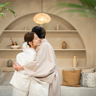 アーチの飾り棚の前で抱き合う、白無垢の花嫁と羽織の新郎。ファーストミートの喜びが伝わる和装前撮り