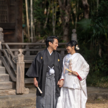 称名寺の古いお堂と竹林を背景に、手をつないで見つめ合う新郎新婦の和装フォトウェディング