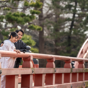 称名寺の朱色の欄干にもたれて笑い合う紋付袴の新郎と白無垢の花嫁。反橋で撮る和装ロケーションフォト