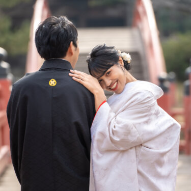 反橋の上で新郎の肩に頬を寄せ、振り返ってほほえむ白無垢の花嫁。称名寺で撮る和装フォトウェディング