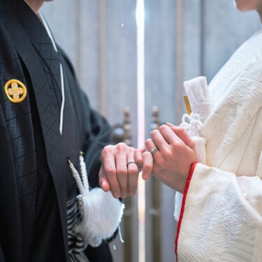 黒紋付の新郎と白無垢の花嫁が指を絡める手元のクローズアップ。和装フォトウェディングのディテール