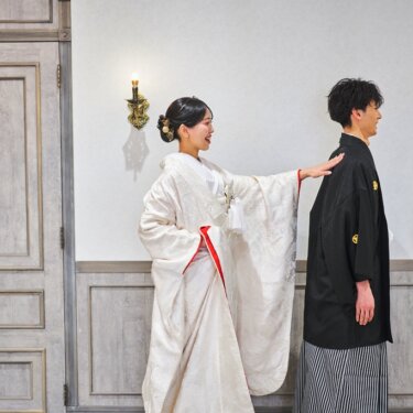 背を向けて待つ紋付袴の新郎の背に、白無垢の花嫁がそっと手を添えるファーストミートの和装前撮り