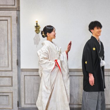 扉の前で白無垢の花嫁が新郎に手を上げてあいさつする、ファーストミート直前の和装フォトウェディング