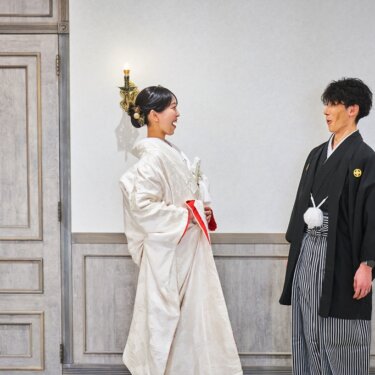 扉の前で向き合い、笑顔がこぼれる白無垢の花嫁と紋付袴の新郎。ファーストミートの和装前撮り
