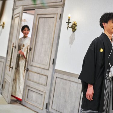 扉の向こうから顔をのぞかせる白無垢の花嫁と、廊下でほほえむ紋付袴の新郎。ファーストミートの和装前撮り