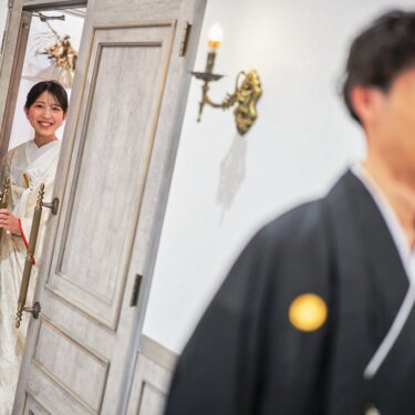 手前の新郎をぼかし、扉からほほえむ白無垢の花嫁にピントを合わせたファーストミートの和装フォトウェディング