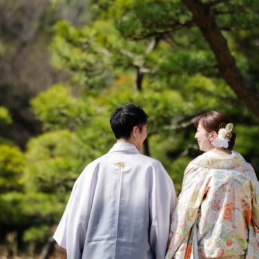 三渓園の松林を背に、振り返って笑い合う新郎新婦の後ろ姿を写した和装ロケーションフォト