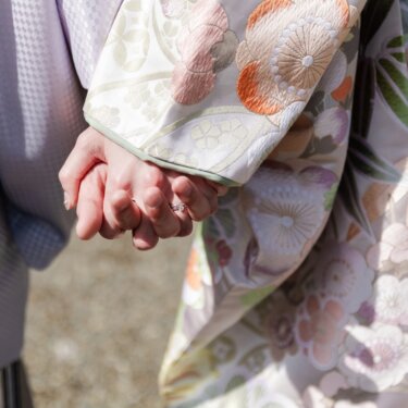 手をつなぐ二人の指輪と、色打掛の菊の刺繍を写したクローズアップ。和装フォトウェディングのディテール