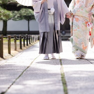 石畳の参道を歩く新郎新婦の足元を和傘の下から写した一枚。袴と色打掛の裾が美しい和装フォトウェディング