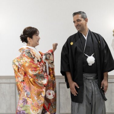 色打掛の花嫁と振り返った紋付袴の新郎が正面から向き合う、笑顔のファーストミートの和装前撮り