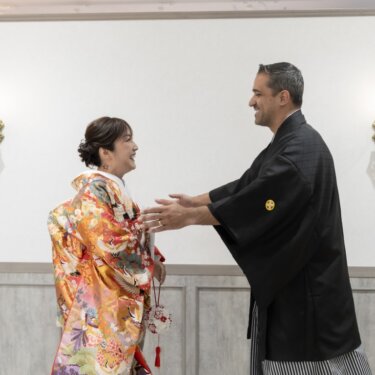 両手を広げて色打掛の花嫁を迎える、感激した表情の紋付袴の新郎。ファーストミートの和装前撮り