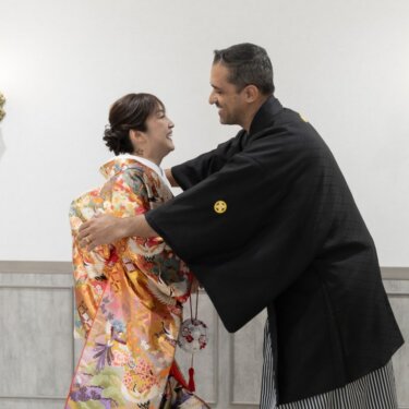 両手を広げて花嫁を抱き寄せる新郎。色打掛姿を初めて見た喜びを写した和装フォトウェディング