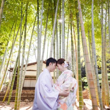 高い竹林の中で額を合わせる新郎新婦を、竹を見上げるように写した和装ロケーションフォト