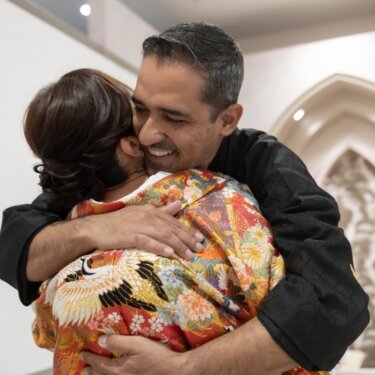 尖塔アーチのセットの前で笑顔で抱き合う新郎と鶴柄の色打掛の花嫁。感動のファーストミートの和装前撮り