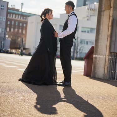 夕暮れの長い影の中、新郎のジャケットを羽織った花嫁と見つめ合う新郎。横浜の街並みで撮る前撮り