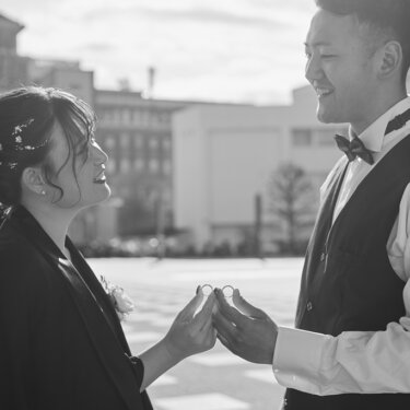 二人で指輪をつまんで見せ合い、笑い合う新郎新婦をモノクロで写した横浜の街ロケの結婚写真