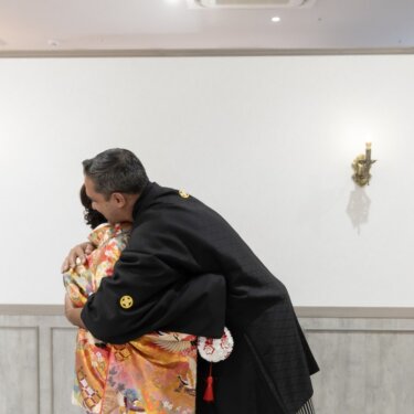 壁灯のある部屋で深く抱き合う新郎新婦を少し引いて写した、ファーストミートの和装フォトウェディング