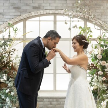花のガーデンセットで、新郎が花嫁の手の甲にキスをするロマンチックなスタジオフォト