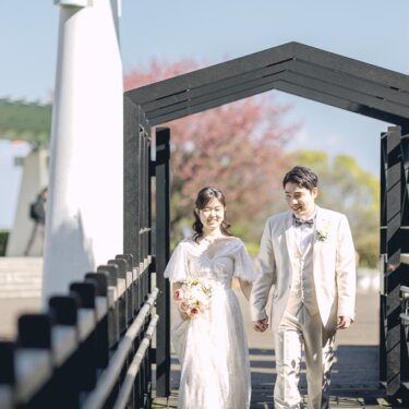 港の見える丘公園の展望台入口のゲートを、手をつないで歩いてくる新郎新婦のロケーションフォト