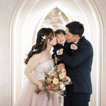 両親に両側からほおにキスされ、笑顔の息子。ほほえましい家族写真のフォトウェディング