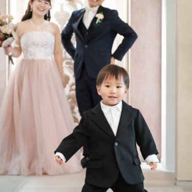 両親の前でポーズを決めるタキシード姿の男の子。カラードレスで撮る家族写真のスタジオフォト