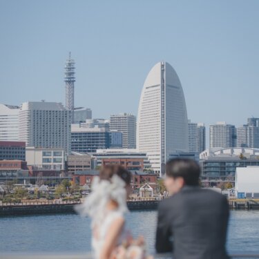 みなとみらいの高層ビル群にピントを合わせ、新郎新婦をぼかした印象的な引きの構図の前撮り