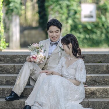 蔦の絡まる石段に腰を下ろし、寄り添って見つめ合うレースドレスの花嫁と新郎の結婚写真