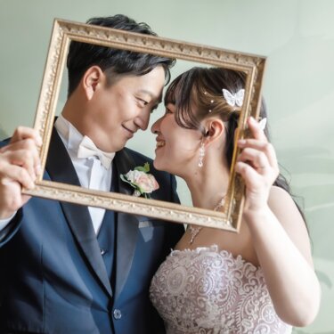金の額縁の中で額を寄せ合う新郎新婦。ミントグリーンの壁で撮る小物使いのスタジオ前撮り
