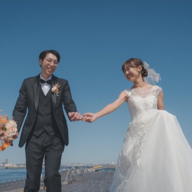 海を望む大さん橋の波形デッキを、ベールをなびかせ手をつないで歩く新郎新婦のロケーションフォト