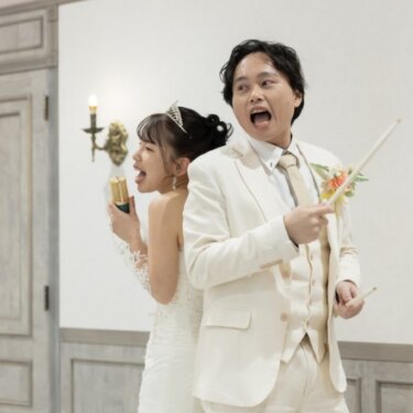 背中合わせでマイクとドラムスティックを持ち、口を大きく開けて熱唱する新郎新婦。遊び心あるウェディングフォト