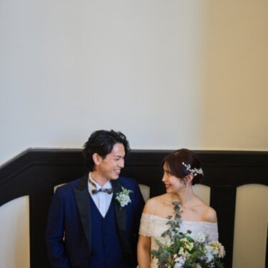 白い壁と黒い手すりの階段で、ブーケを持って見つめ合う新郎新婦。クラシカルな洋館のウェディングフォト