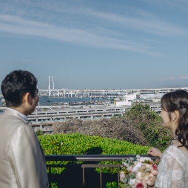 港の見える丘公園の展望台から、ベイブリッジと横浜港の景色を眺める新郎新婦の後ろ姿の前撮り