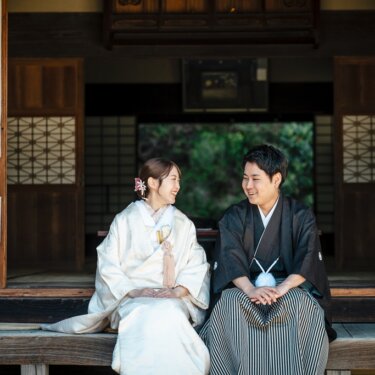 古民家の縁側に並んで腰かけ、笑い合う白無垢の花嫁と黒紋付袴の新郎。横溝屋敷で撮る和装前撮り