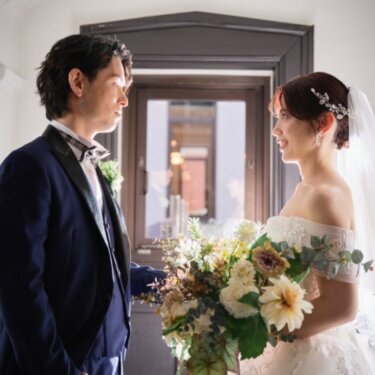 重厚な扉のある部屋で見つめ合う、ネイビーのタキシードの新郎とベールをつけた花嫁の結婚写真