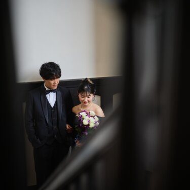 階段の手すり越しにのぞくように写した、寄り添う新郎新婦。洋館の陰影が美しいウェディングフォト