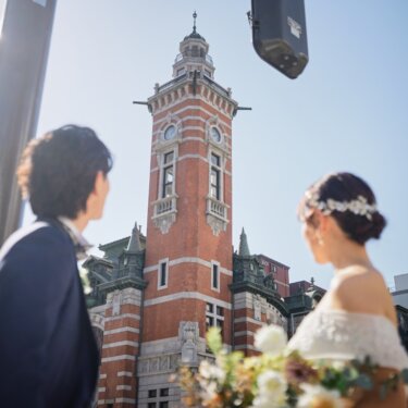横浜市開港記念会館の時計塔にピントを合わせ、手前の新郎新婦をぼかした印象的な構図の結婚写真