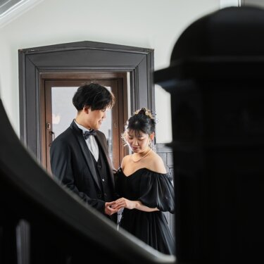階段の手すり越しに、扉の前で指輪を見つめ合う新郎新婦を写した洋館でのウェディングフォト