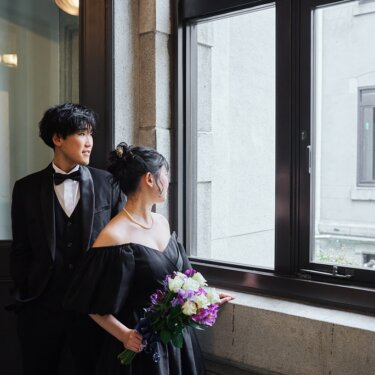 横浜の洋館の大きな窓から外を並んで眺める新郎新婦。黒いカラードレスで撮るクラシカルなフォトウェディング