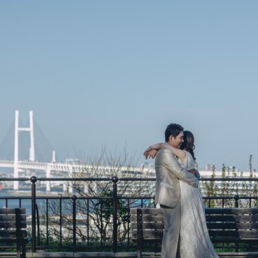 横浜ベイブリッジと海を背に、展望台で抱き合う新郎新婦。ハグのポーズで撮る港の見える丘公園の結婚写真