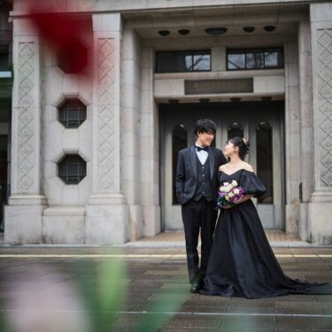 花を前景にぼかし、歴史的な石造りの建物の入口に立つ新郎新婦を写したクラシカルなロケーションフォト