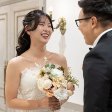 新郎と向き合って大笑いするブーケの花嫁。笑顔あふれるファーストミートのスタジオフォト