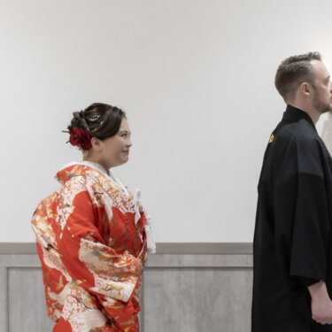壁灯のある部屋で、背を向けて待つ紋付袴の新郎と後ろで待つ色打掛の花嫁。ファーストミート前の和装フォトウェディング