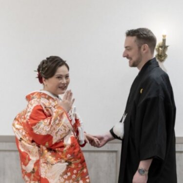口元に手を添えてほほえむ色打掛の花嫁と、その手を取る紋付袴の新郎。ファーストミートの和装前撮り