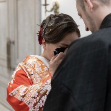 新郎の胸に顔を寄せて涙ぐむ赤い色打掛の花嫁。感動のファーストミートを写した結婚写真